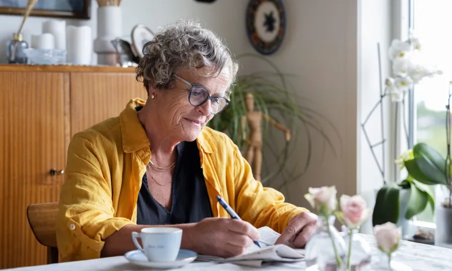 Immagine di Gullborg seduta al tavolo con un caffè e un giornale. I problemi alla vescica non sono rari quando si convive con la sclerosi multipla. Infatti, più di 4 persone su 5 affette dalla patologia sono colpite da problemi di incontinenza ad un certo punto della loro vita. 