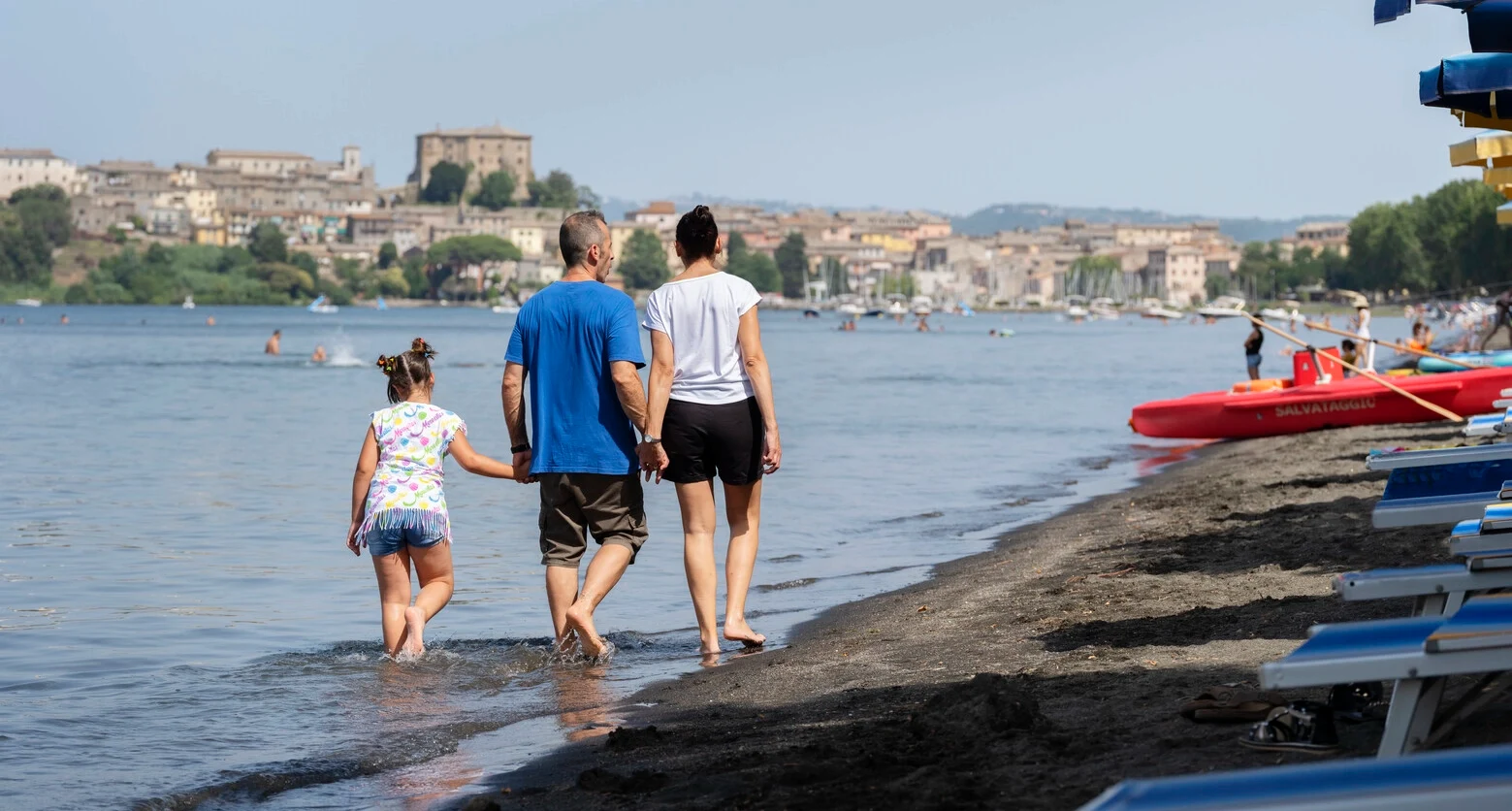 Foto di Andrea che passeggia sulla spiaggia con la sua famiglia. Andrea convive con la sclerosi multipla e utilizza la TAI per gestire i problemi intestinali. 