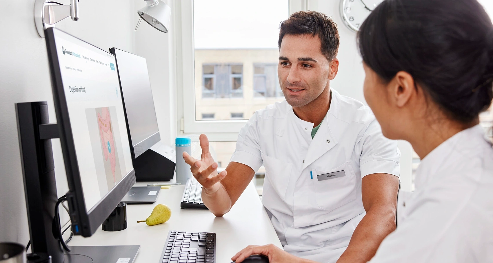 Foto di due operatori sanitari seduti davanti a un computer. La sclerosi multipla può causare disfunzioni intestinali. Esistono diversi trattamenti per gestire i sintomi  