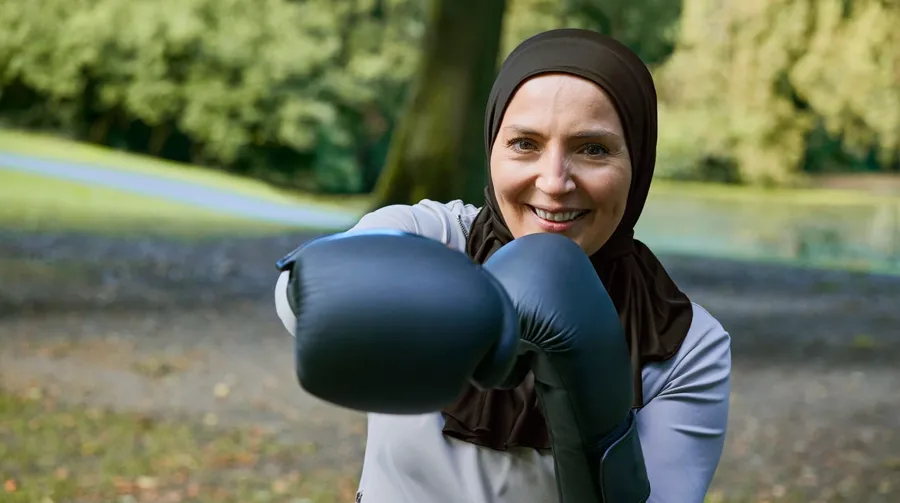 Foto di Fikria in un parco mentre si allena con i guantoni da boxe. Ora che Fikria ha un miglior controllo dell'intestino, può fare esercizio fisico come preferisce e si sente più sicura di sé.  