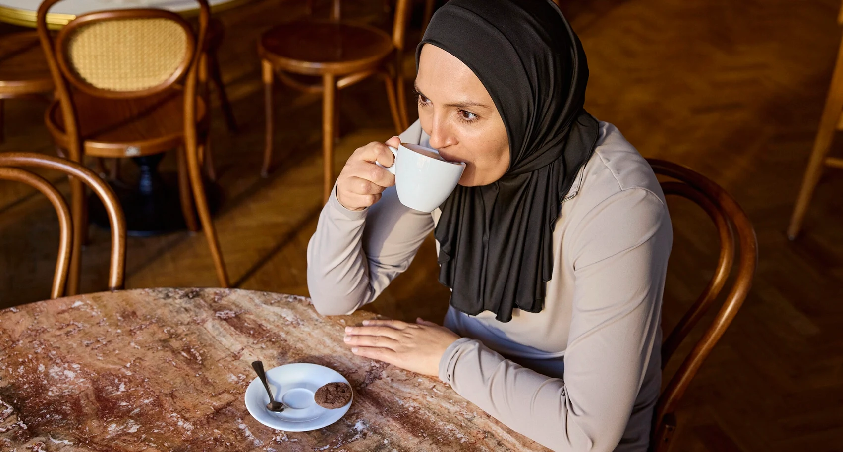 Ritratto fotografico di Fikria seduta in un bar. Fikria convive con la sclerosi multipla e i problemi intestinali fanno parte della sua vita. 