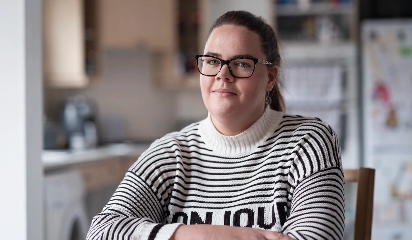 Sarah, affetta da sclerosi multipla e utilizzatrice di cateteri intermittenti, è seduta a un tavolo. 