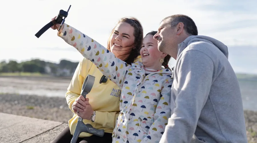 Foto di Sarah e della sua famiglia mentre scattano un selfie sulla spiaggia. Sarah ha impiegato molto tempo per collegare i suoi problemi vescicali alla sclerosi multipla.