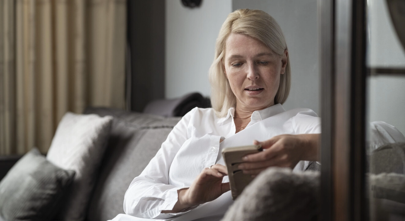 Immagine di Ilse seduta nel suo salotto. La sclerosi multipla provoca danni al sistema nervoso, interrompendo i messaggi provenienti dal cervello e può quindi interferire con una vasta gamma di funzioni corporee. La vescica può essere particolarmente soggetta a disturbi.  