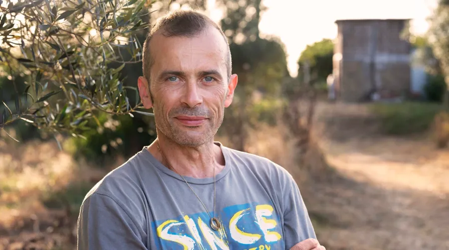 Foto ritratto di Andrea all'aperto. Andrea soffre di sclerosi multipla e utilizza la TAI per gestire i suoi problemi intestinali.  