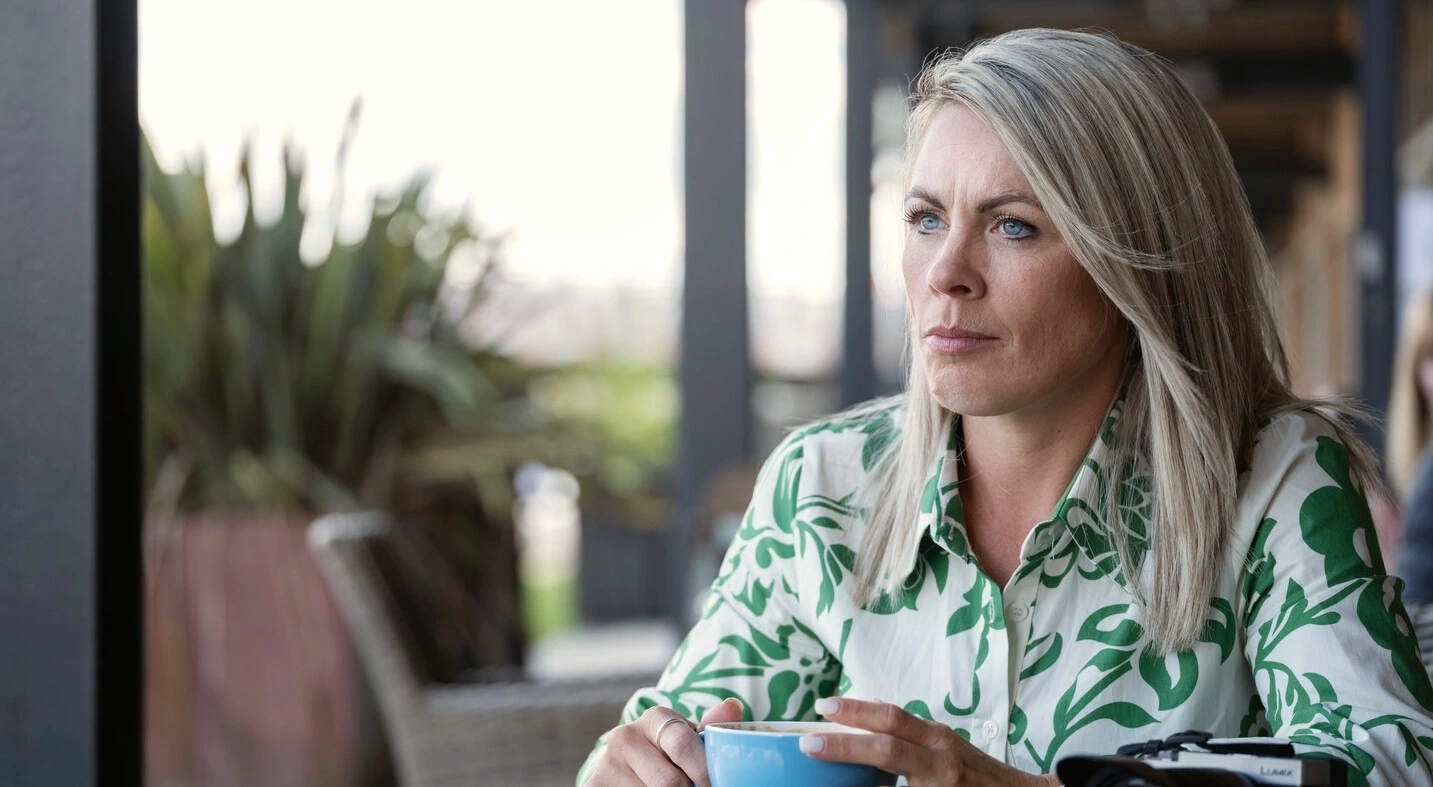 Foto di Laura seduta a un tavolo con una tazza di caffè. Questo articolo fornisce supporto e suggerimenti pratici per la quotidianità e la gestione vescicale e intestinale. 